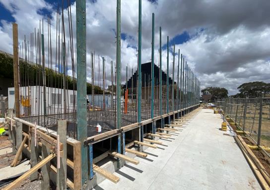 Construction site with vertical beams and a long, concrete walkway