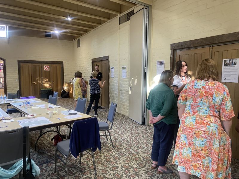 Small groups of people gathered around posters displayed on a wall.